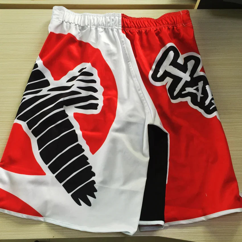 Red and white fight shorts with black crow graphic and bold HA design on table
