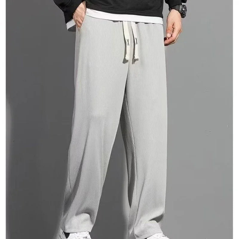 Man wearing light gray wide-leg ribbed knit pants with drawstring waist and side pockets