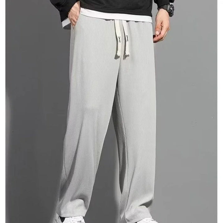 Man wearing light gray wide-leg ribbed knit pants with drawstring waist and side pockets