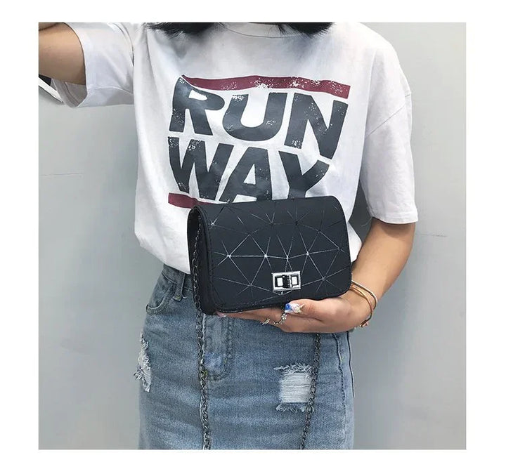 woman wearing white RUNWAY t-shirt and ripped denim skirt holding black geometric shoulder bag with chain strap