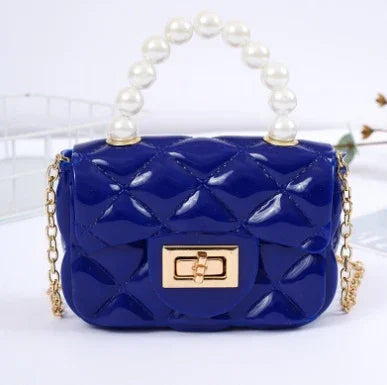 Glossy dark blue quilted handbag with gold clasp, pearl handle, and gold chain strap on white background