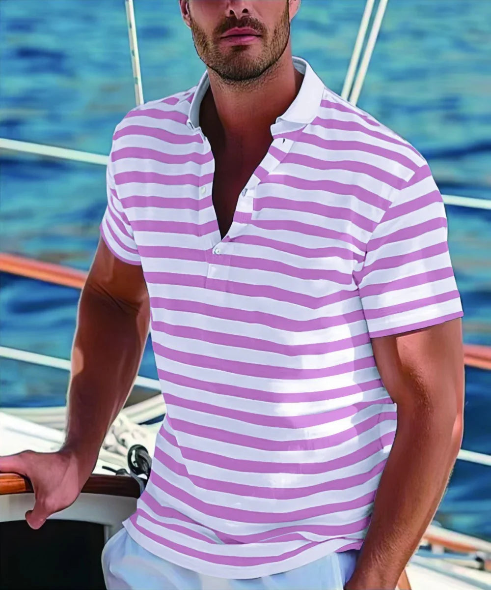 Man in pink and white striped polo shirt standing on a boat with ocean background
