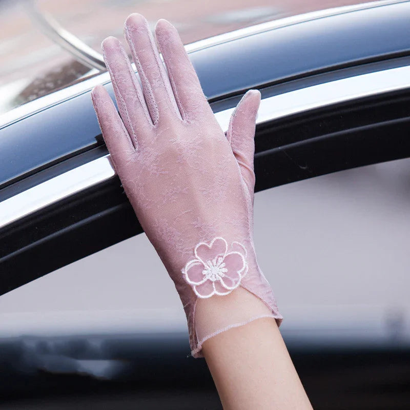 Light pink lace glove with floral embroidery on wrist, hand resting on car window frame