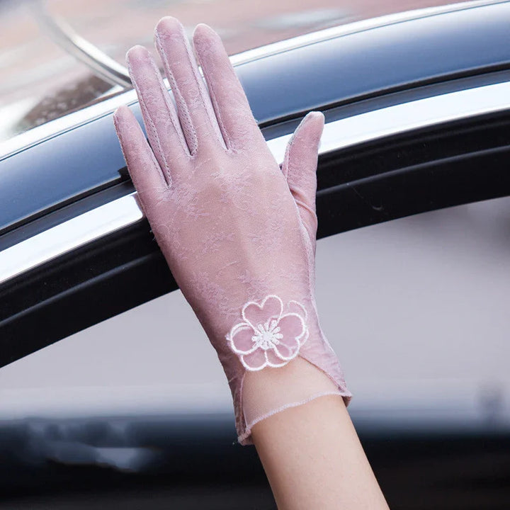 Light pink lace glove with floral embroidery on wrist, hand resting on car window frame
