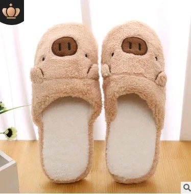 Pair of beige plush pig face slippers on wooden floor with white curtain background