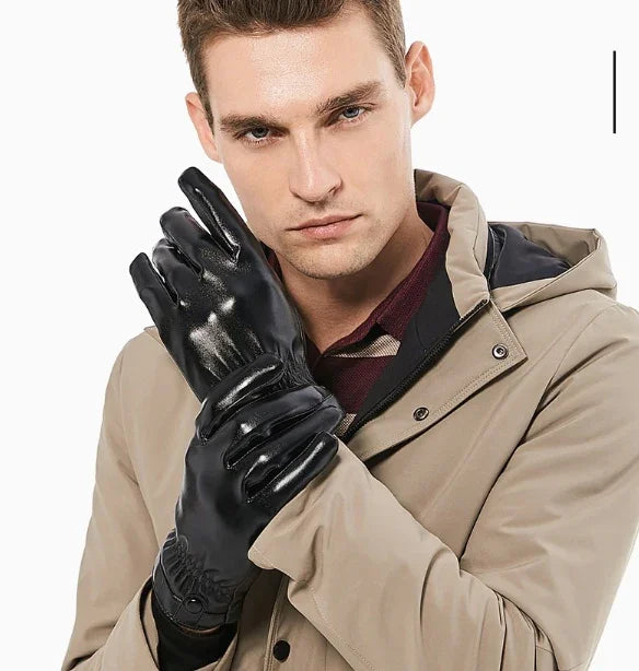 Man wearing shiny black leather gloves and a beige jacket with a hood, posing against white background