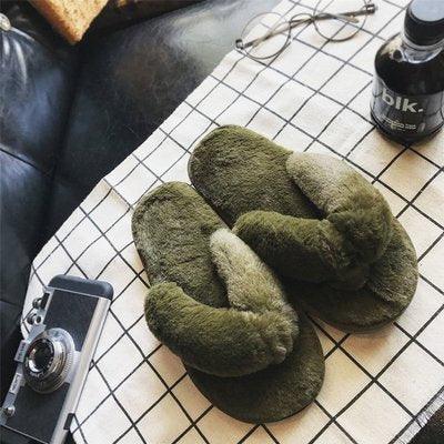 Cozy olive green fuzzy slippers on white grid fabric with vintage camera, black bottle, and eyeglasses
