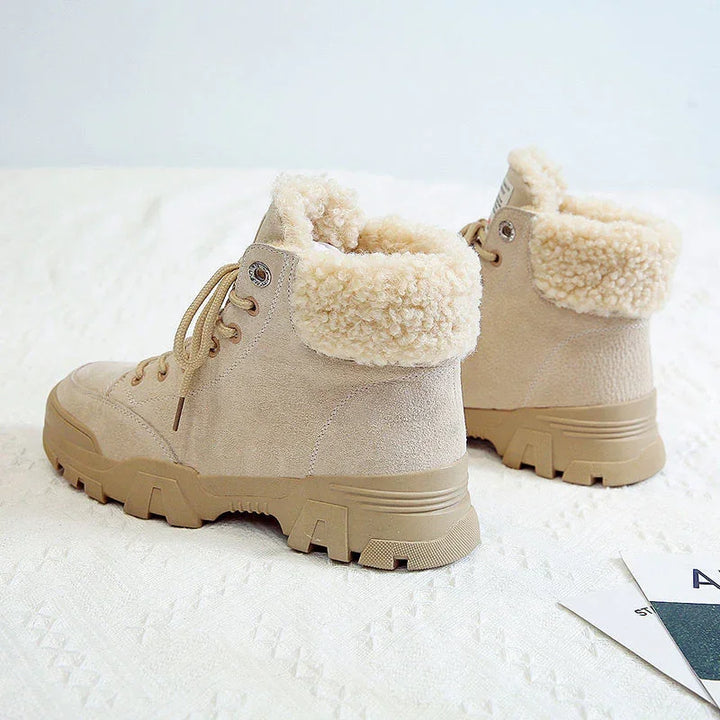Beige winter boots with shearling collars and lace-up design on textured surface