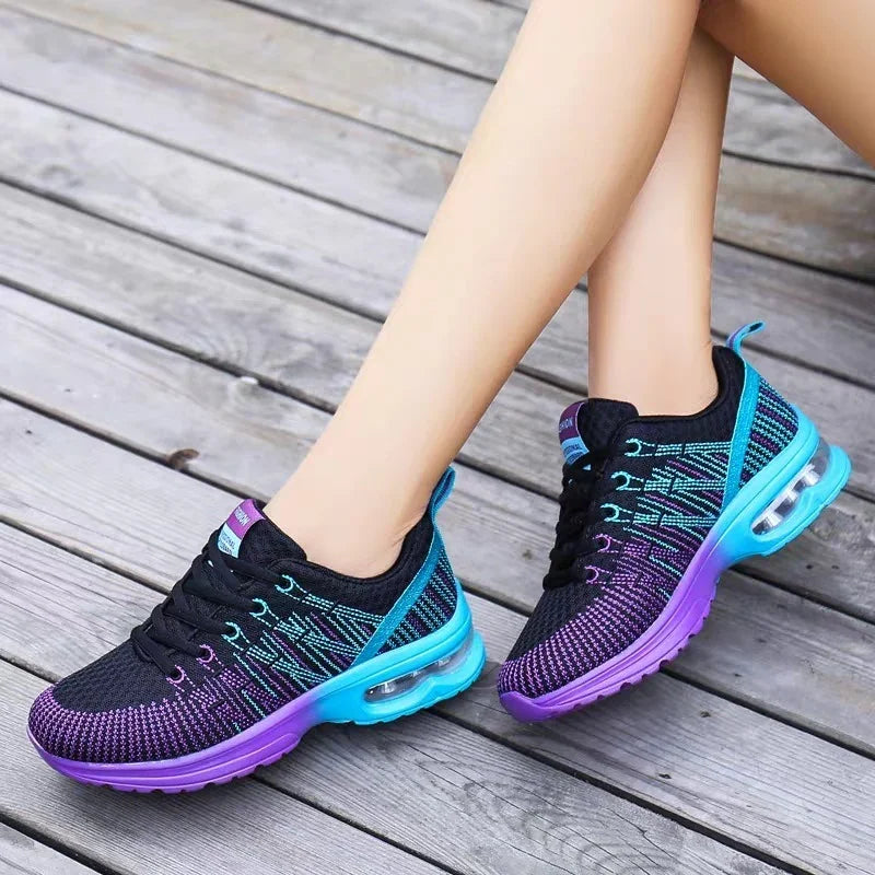Black, blue, and purple knitted athletic sneakers with air cushion sole worn on wooden deck