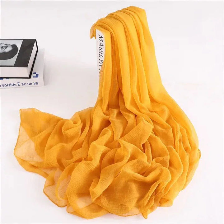 Soft mustard yellow chiffon scarf arranged over a white book, shown with black and white photo book