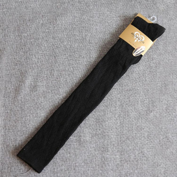 Pair of black knee-high socks with packaging on gray textured fabric background