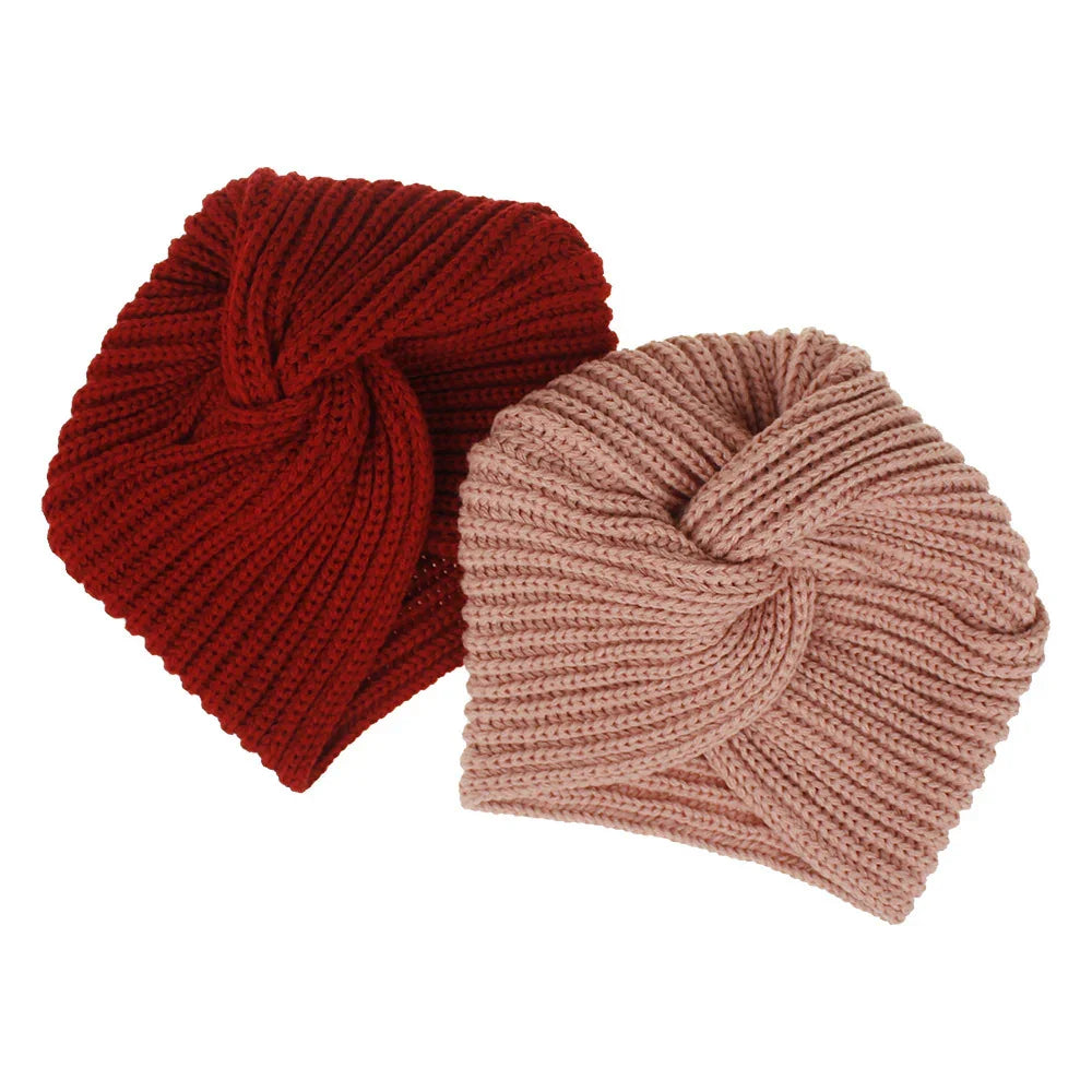 Two knitted turban-style headbands in red and light pink on white background