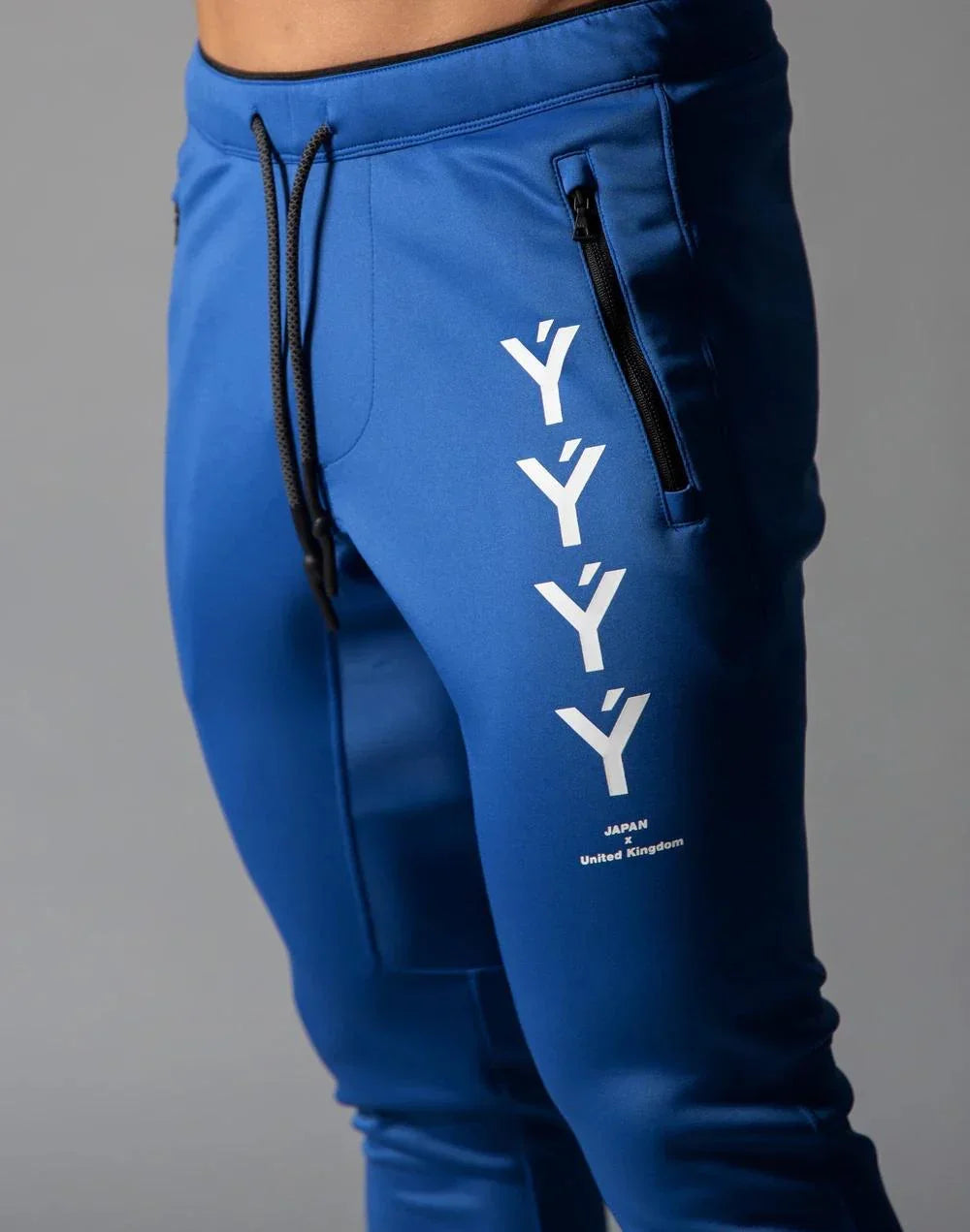 Blue jogger pants with black drawstring and white Y-shaped graphic with Japan x United Kingdom text