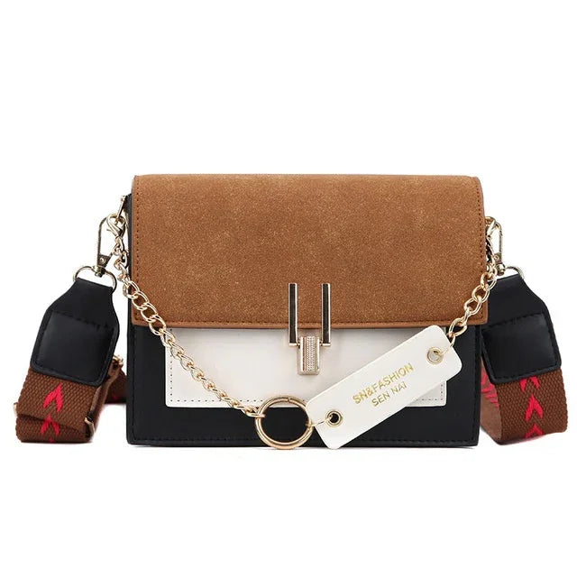 Small colorblock crossbody bag with brown suede flap, white and black body, gold chain, and wide brown strap