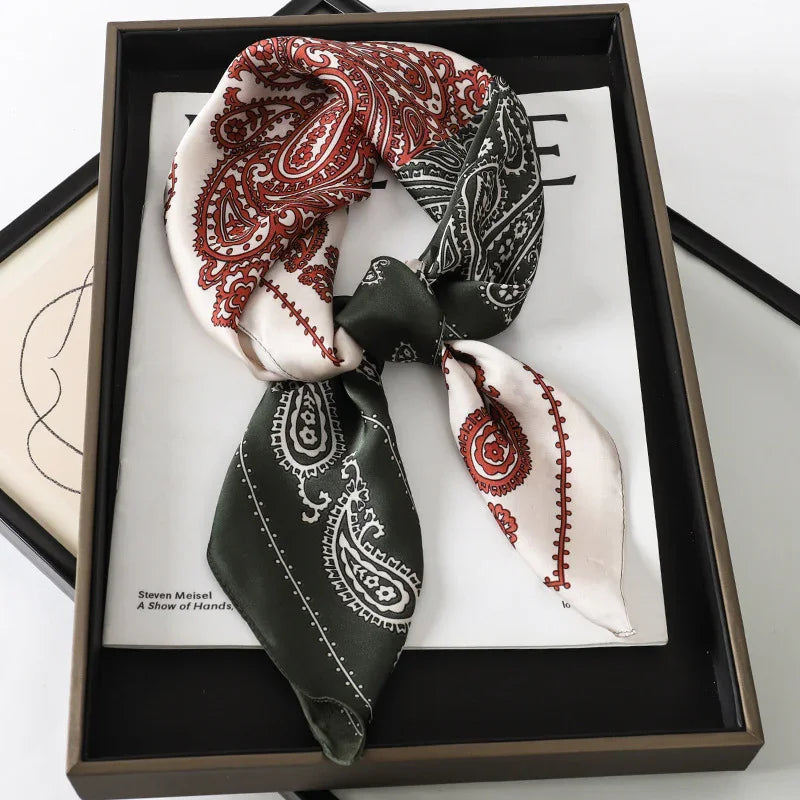 Silk scarf with red and black paisley design, artfully knotted in black tray with magazine background