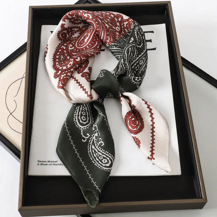 Silk scarf with red and black paisley design, artfully knotted in black tray with magazine background