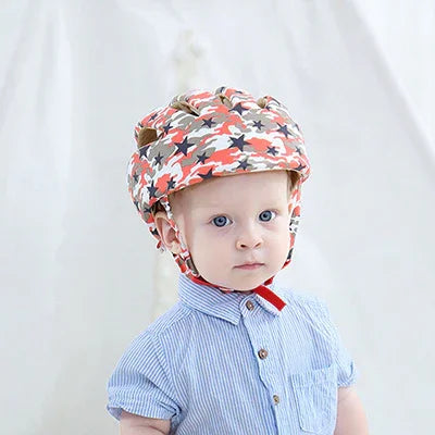 Toddler wearing a colorful star-patterned baby helmet and blue striped shirt against white background