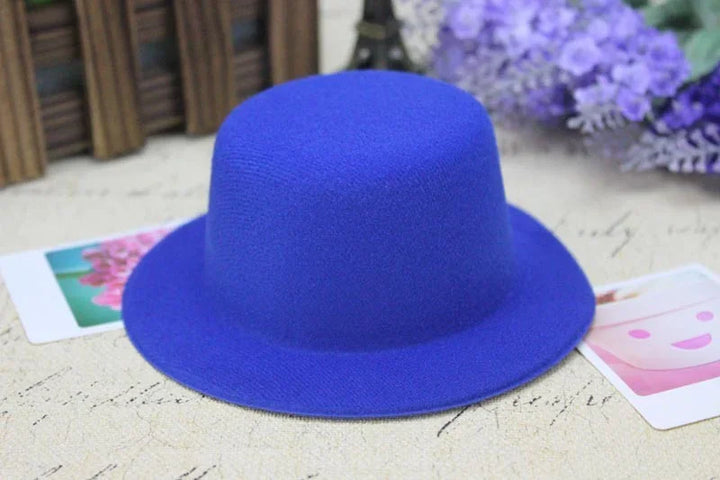 Bright blue felt hat with a rounded crown on a textured surface with purple flowers and colorful cards