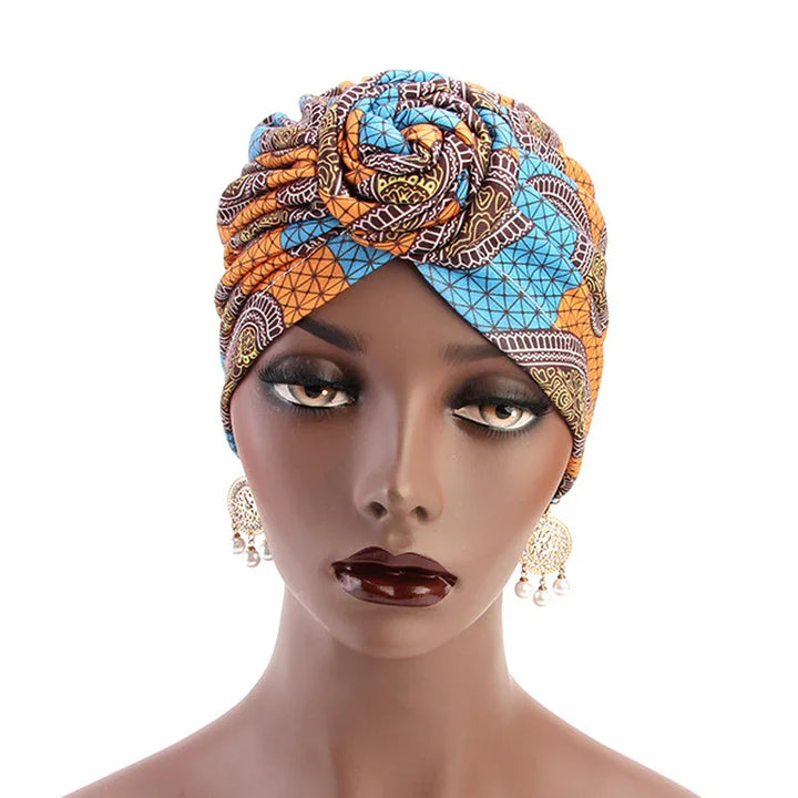 Woman mannequin wearing colorful African print turban headwrap with rose design and dangling earrings