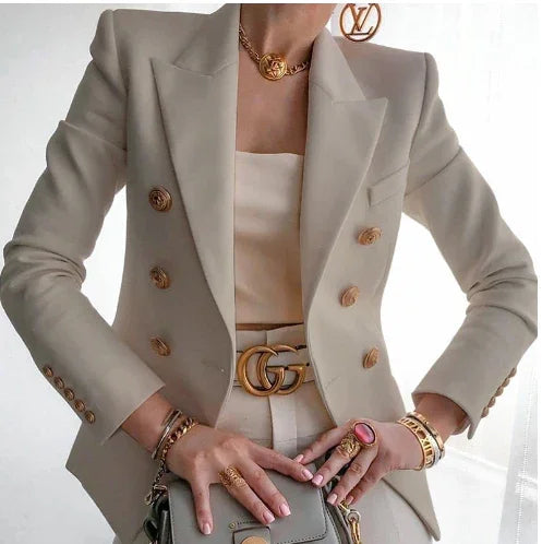 Woman wearing beige double-breasted blazer with gold buttons, Gucci belt, and luxury jewelry holding gray designer handbag