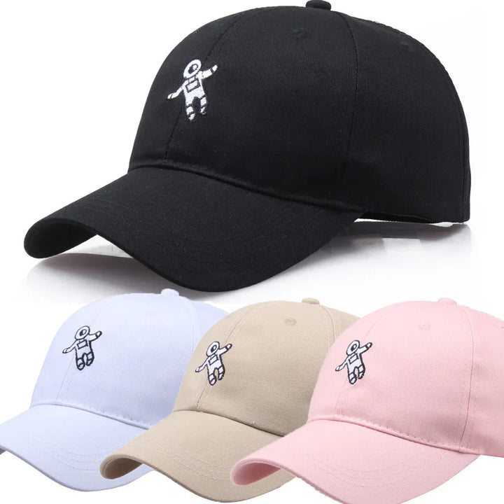 Four baseball caps in black, white, beige, and pink with small embroidered astronaut design