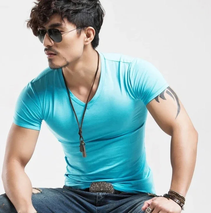 Stylish man wearing blue V-neck t-shirt, sunglasses, necklace, tattoo, and bracelets