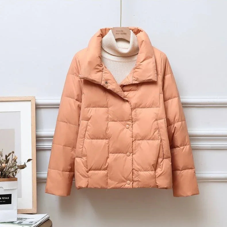 Light orange quilted puffer jacket with large collar over white ribbed turtleneck sweater on hanger