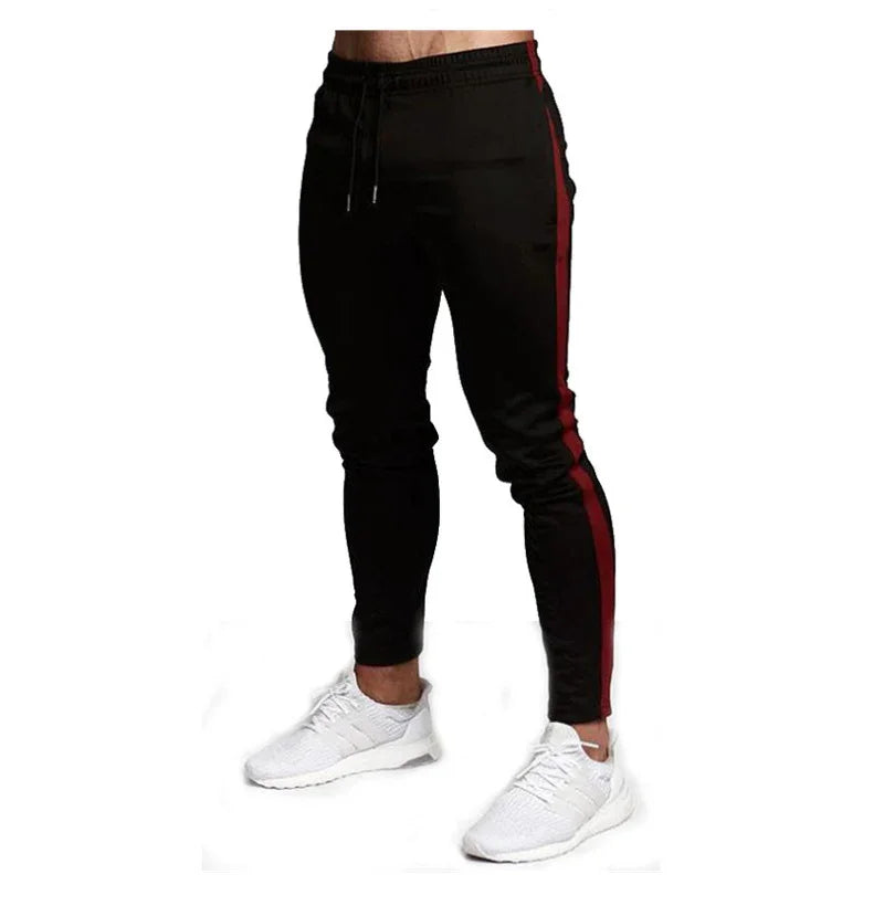 Black men's slim jogger pants with red side stripes and white sneakers on model