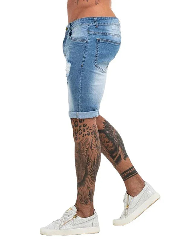 Male model wearing faded blue denim shorts and white casual sneakers showcasing full leg tattoo art