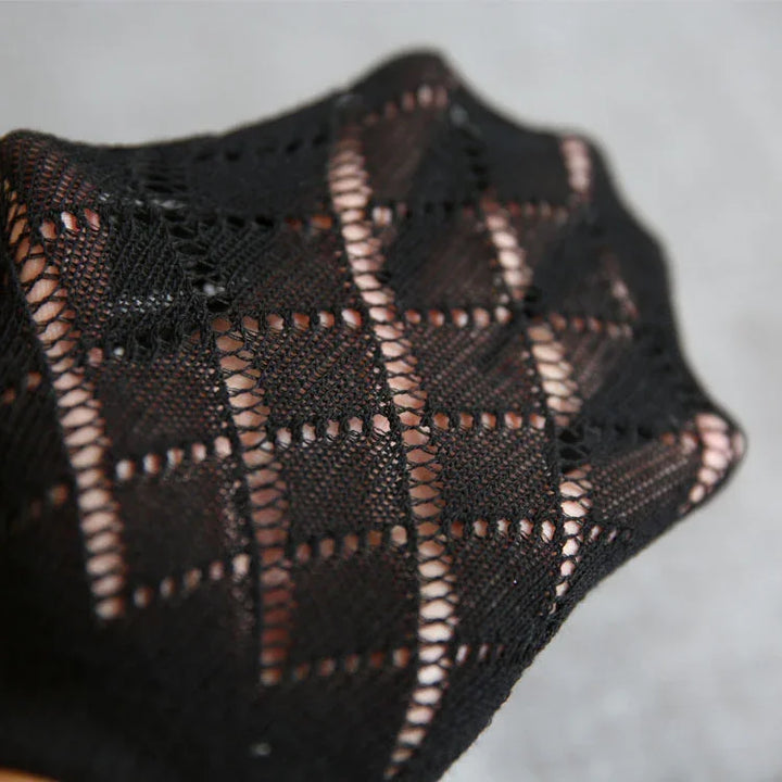 Close-up of black lace fabric with geometric pattern showing intricate knitting details