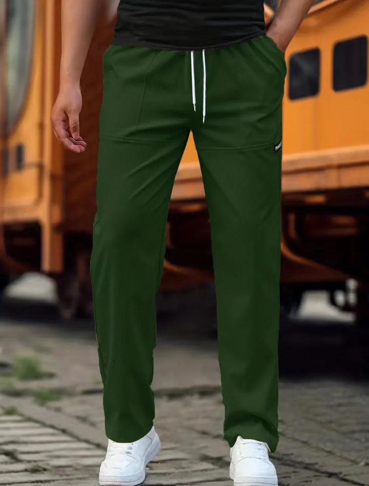 Man wearing olive green casual pants with white drawstring and white sneakers on cobblestone street