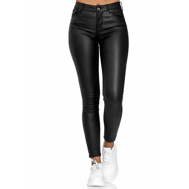 High-waisted black leather skinny pants paired with white sneakers on a model