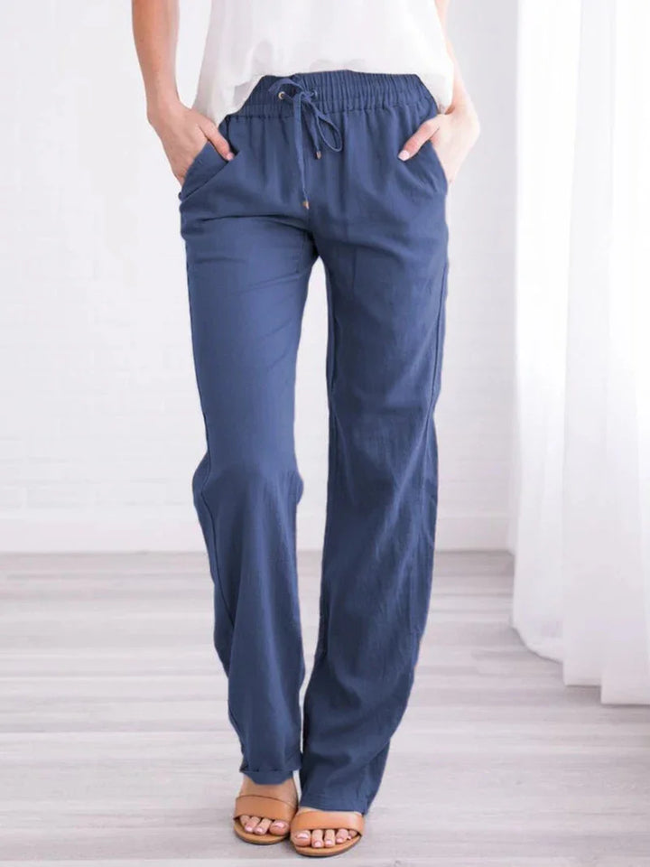 Woman wearing navy blue drawstring linen pants paired with open-toe sandals in bright room