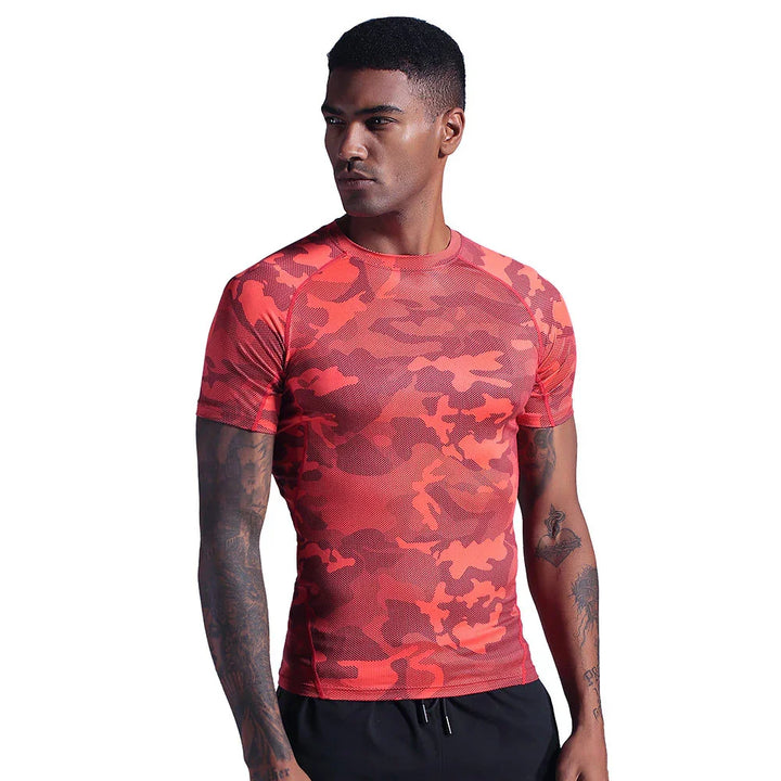 Male model wearing a red camouflage athletic t-shirt with black shorts against white background