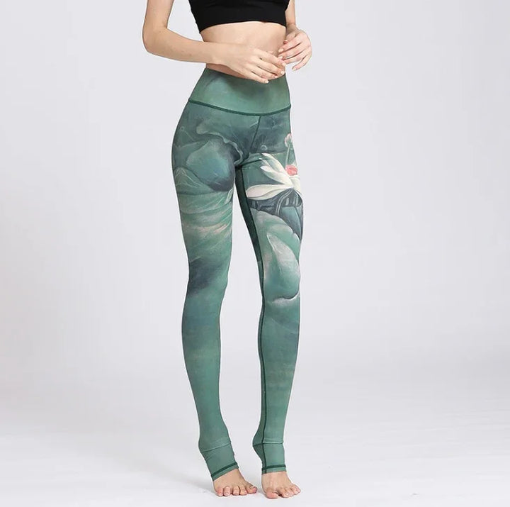 Woman wearing high-waisted green leggings with floral lotus design and black crop top
