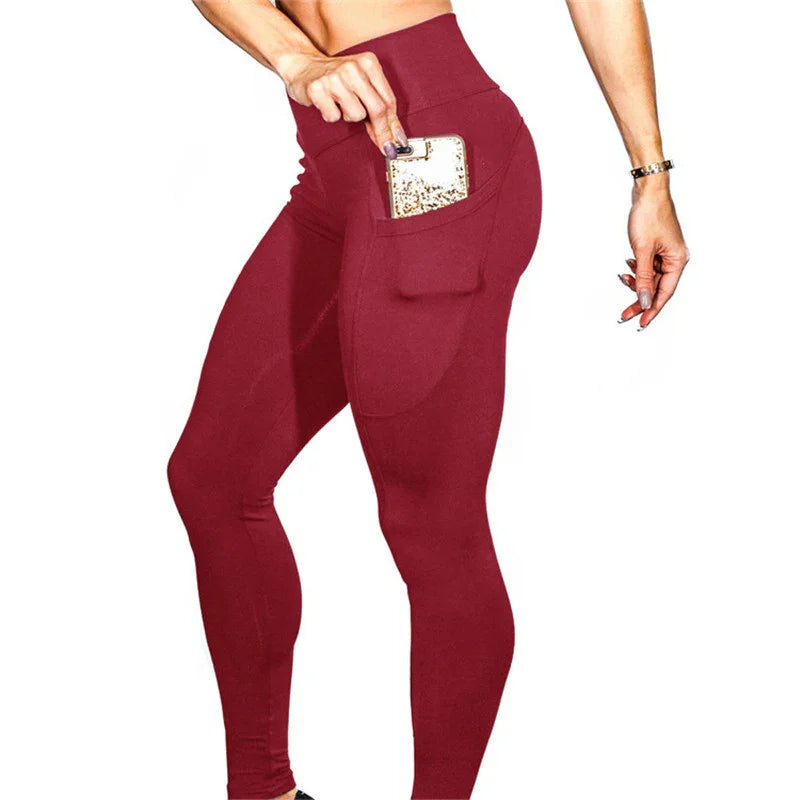 Woman wearing high-waisted burgundy leggings with a side pocket holding a gold smartphone