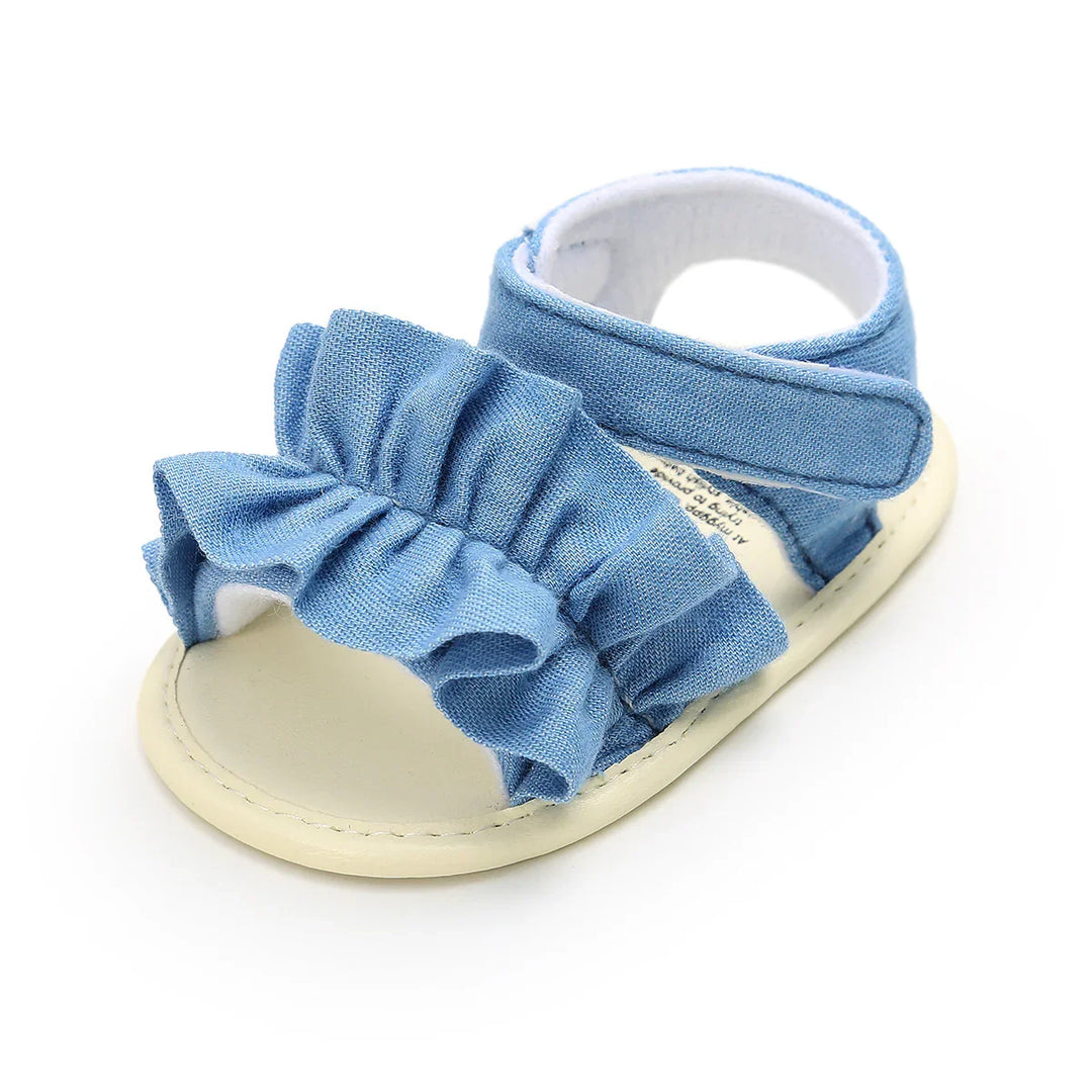 Light blue baby sandal with ruffle detailing and beige sole on white background