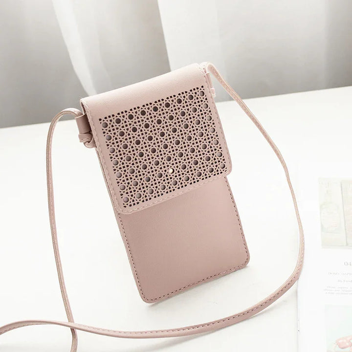 Light pink leather crossbody phone bag with perforated floral design flap on white surface