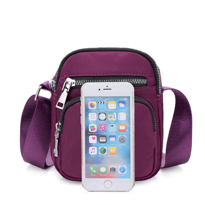 Compact purple crossbody bag with multiple zippered compartments and adjustable shoulder strap