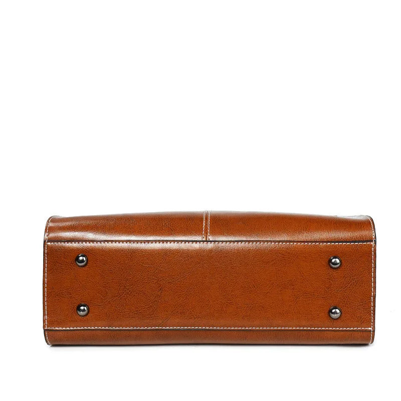 Bottom view of brown leather handbag with white stitching and four metal feet