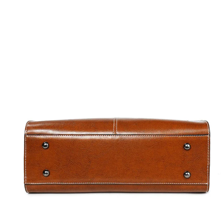 Bottom view of brown leather handbag with white stitching and four metal feet