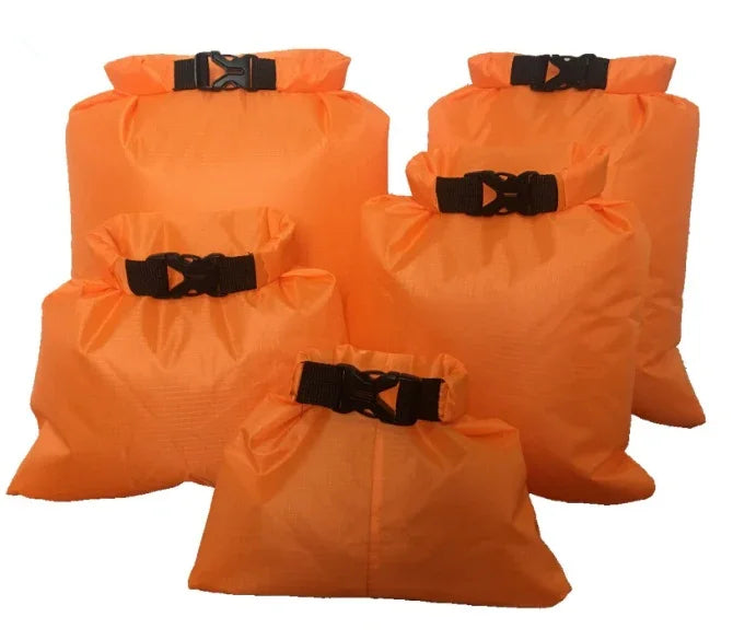 Set of five orange waterproof dry bags with buckle closures, camping gear storage.