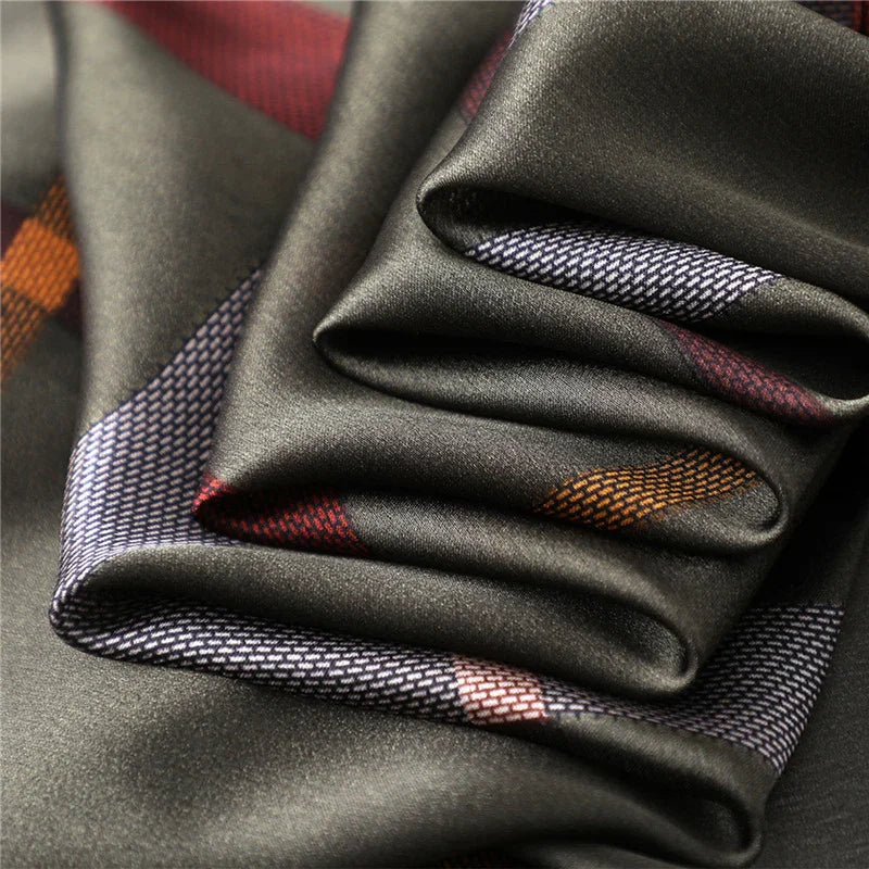 Close-up of smooth black fabric with folded edges and geometric orange, red, and white patterned accents