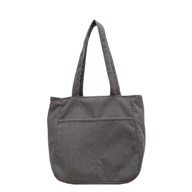 Gray corduroy tote bag with long handles and front pocket on white background