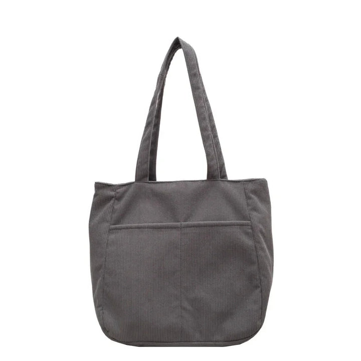 Gray corduroy tote bag with long handles and front pocket on white background