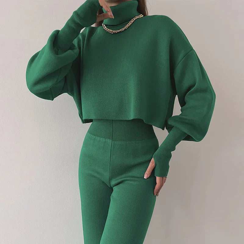Woman wearing green knit high-waisted pants and matching cropped turtleneck sweater with gold chain necklace