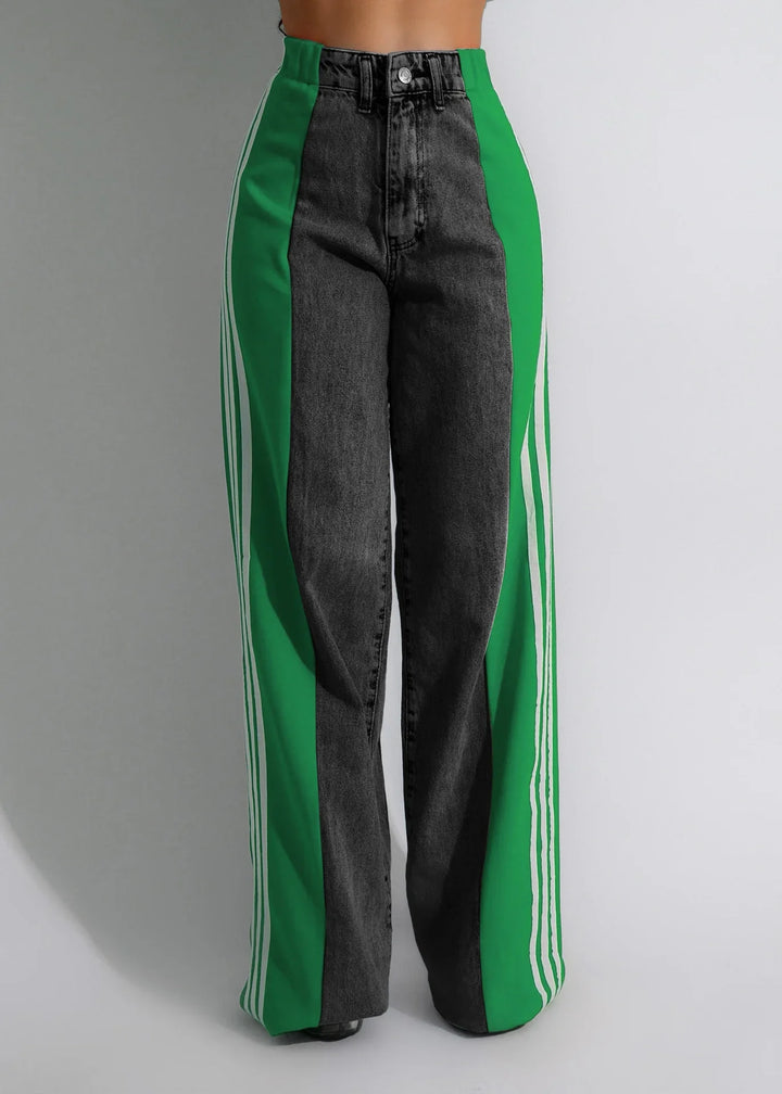 High-waisted black jeans with wide green side panels and white stripes, on model against plain background