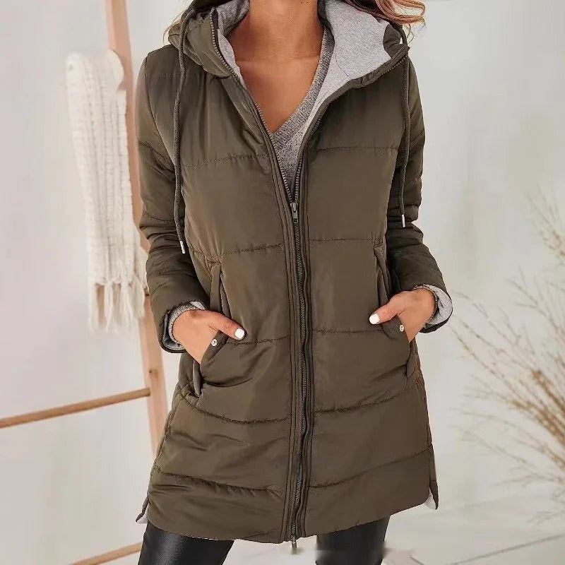 Woman wearing olive green padded winter jacket with hood and zippered front, hands in pockets