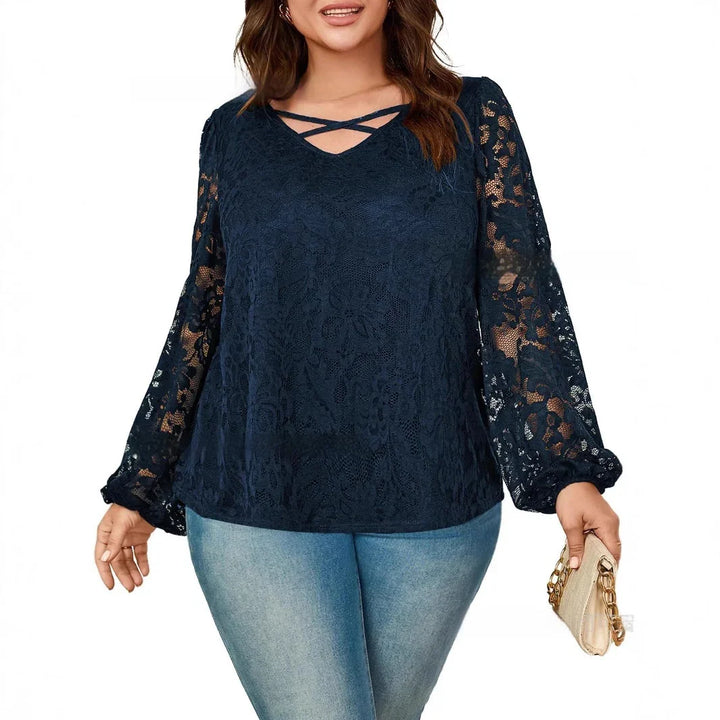 Plus size woman wearing navy blue lace blouse with puff sleeves and cross strap neckline holding beige clutch