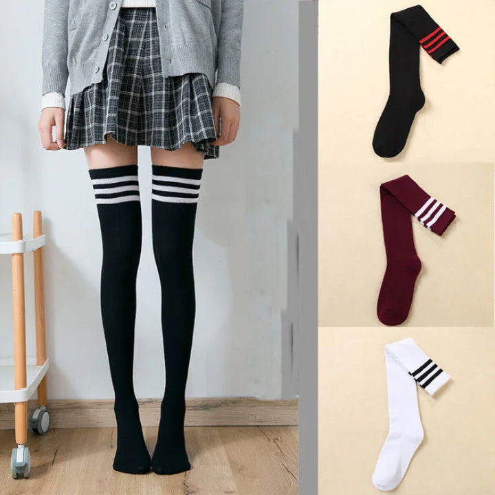 Woman wearing black thigh-high socks with white stripes and a plaid skirt, displayed alongside black, maroon, and white striped socks